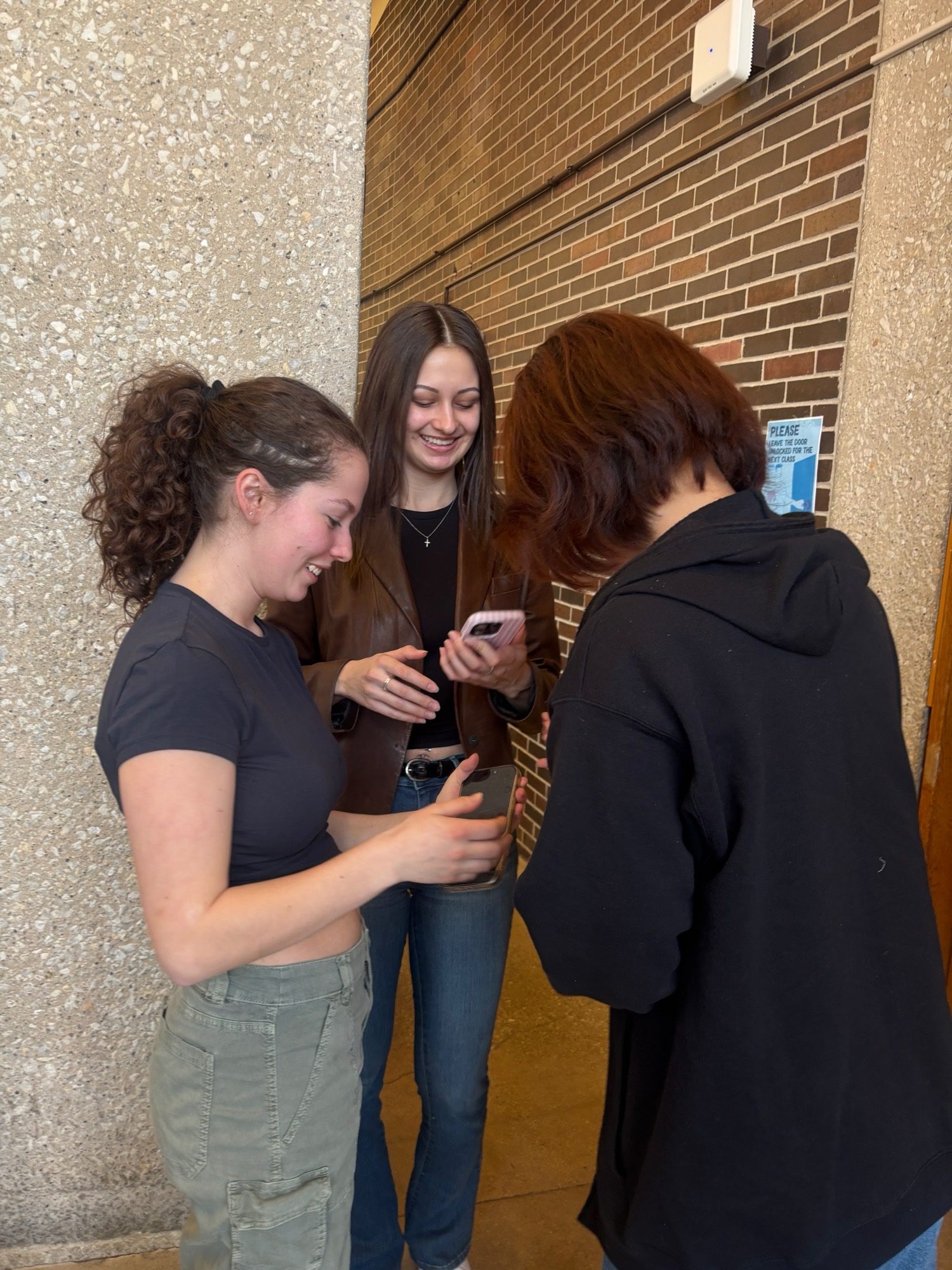 Three UIC students laughing together over their phones after being matched